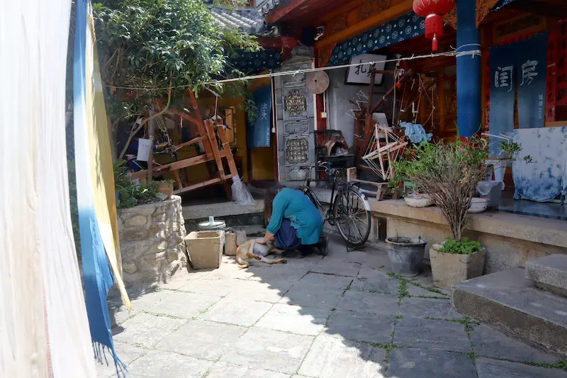 A British guest playing with a dog inside an ancient Chinese house during a tie-dye workshop.