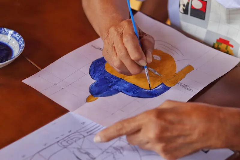 A Buddha figure being drawn and painted.