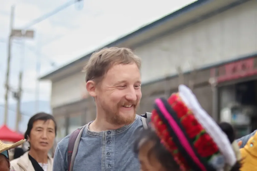 A German male guest smiling at a local market in Yunnan.