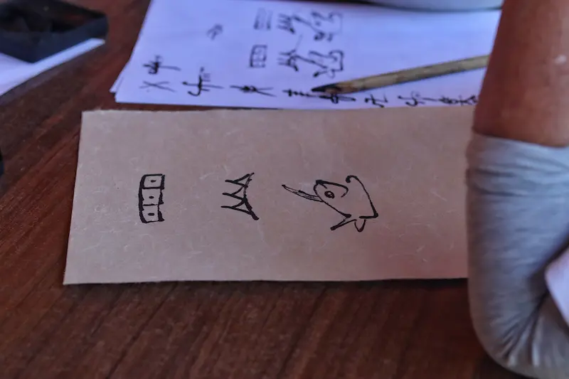 A Singaporean guest writing her name in Naxi Dongba pictographic script.