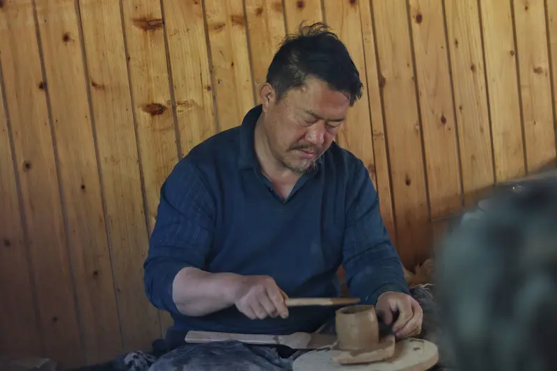 A Tibetan black pottery artisan working on a cup.