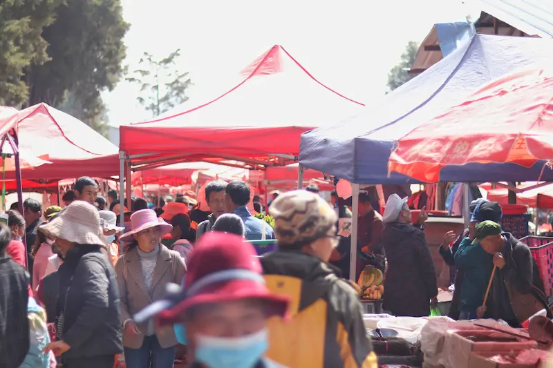 A Yunnan ethnic minority farmers’ market with locals selling, buying, and browsing.