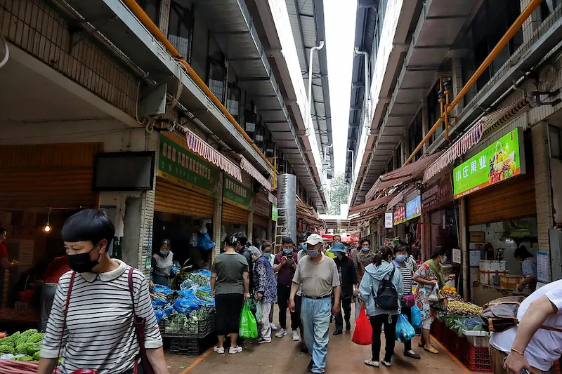 A local wet market in Kunming with residents walking, shopping, and going about their daily routines.