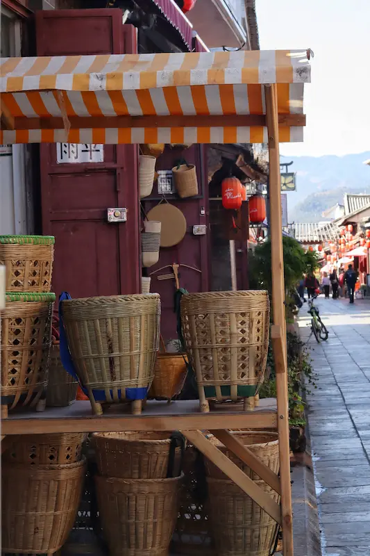 A small booth displaying traditional bamboo baskets along an old town street.