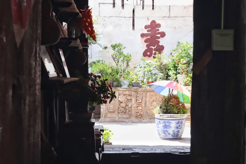 A traditional Chinese house with a white wall and a large red “壽” character meaning longevity.