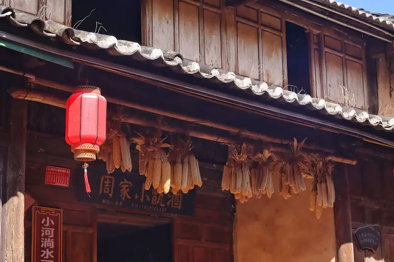 A traditional wooden house with dried corn kernels hanging at the front.