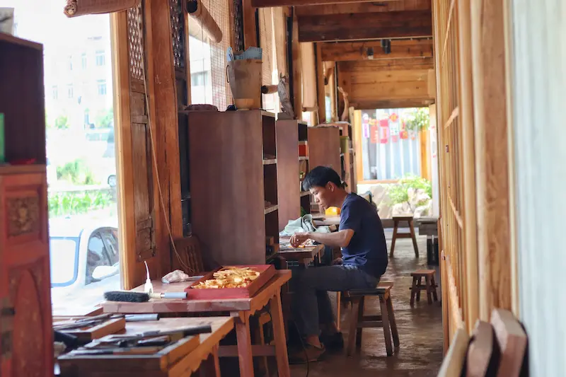 A wood carving artisan working at his station in Dali.