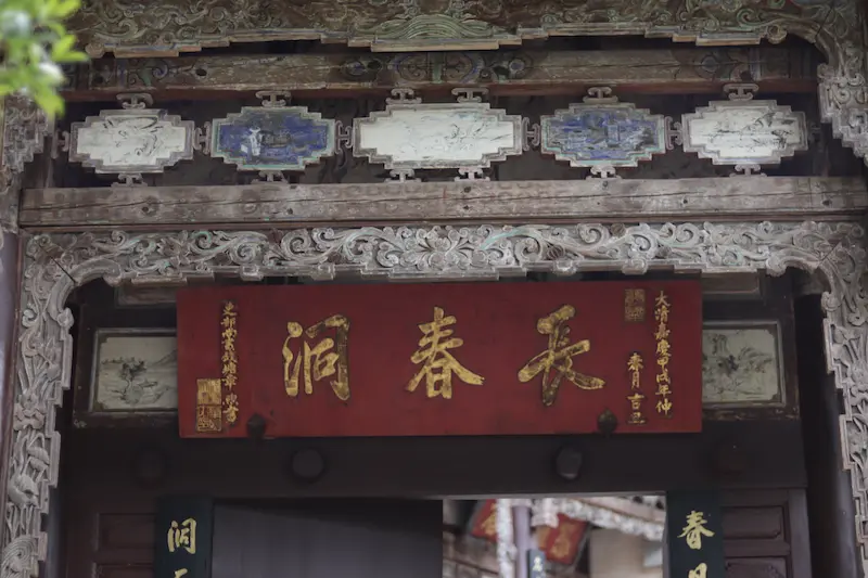Carved wooden temple entrance with red and gold Chinese signboard at a Taoist temple, Weibaoshan, Weishan, Yunnan
