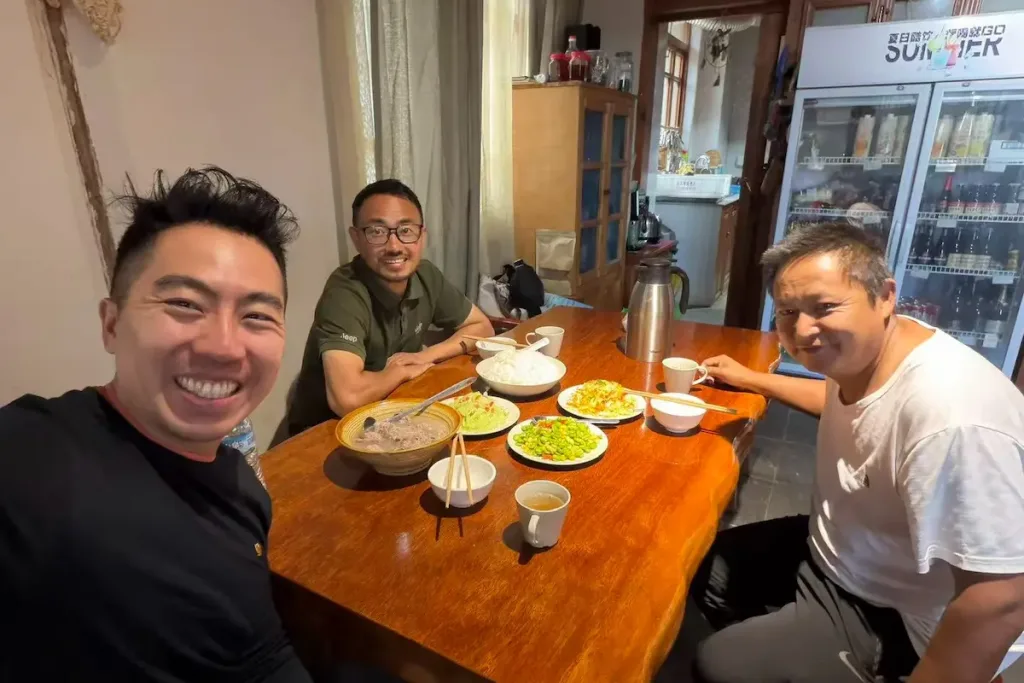 Dali/Lijiang driver Mu smiling and enjoying a meal with a guest from the United States.