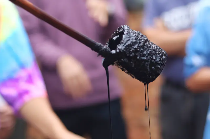 Dark, thick traditional soy sauce dripping from a bamboo ladle.