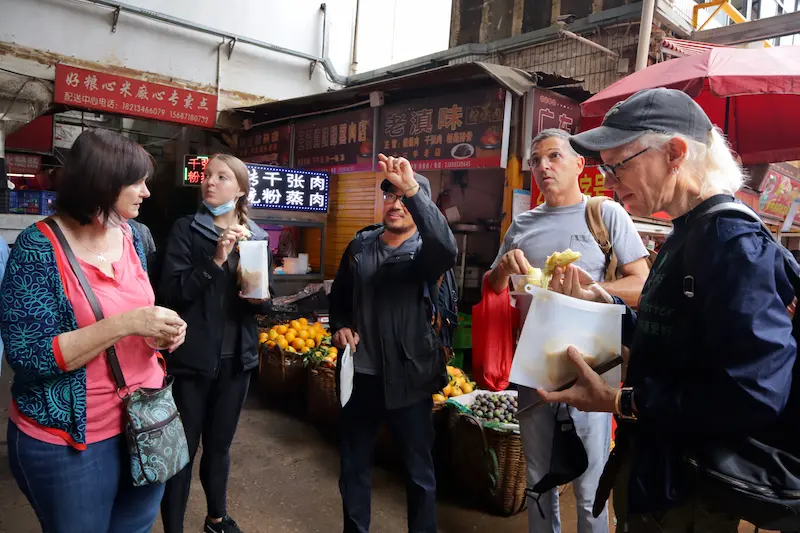 Leo showing four Western guests around a local market in Kunming.