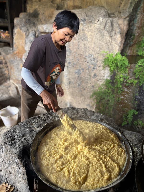 Local woman preparing feed for animals inside a traditional stone house in Stone Village, Lijiang, Yunnan