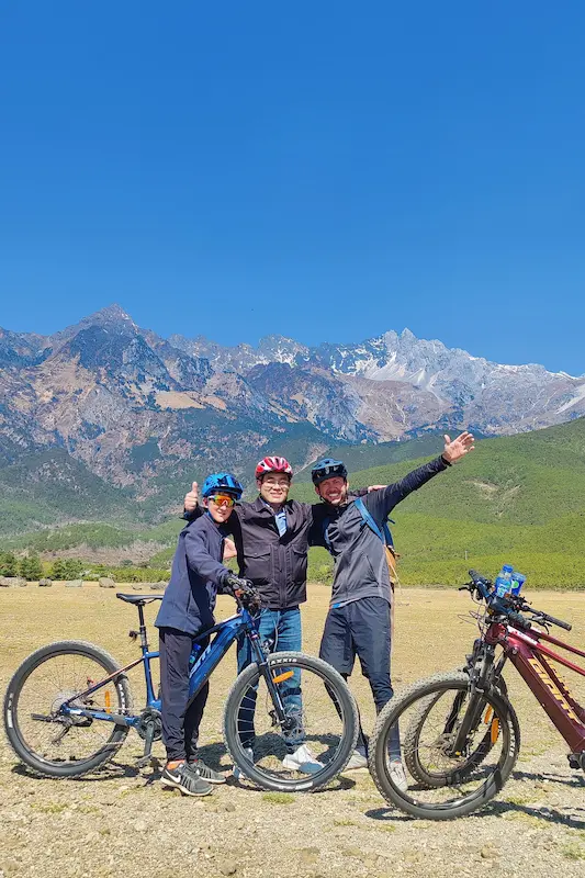 Mountain bikers posing with their bikes in front of Jade Dragon Snow Mountain, Lijiang, Yunnan.