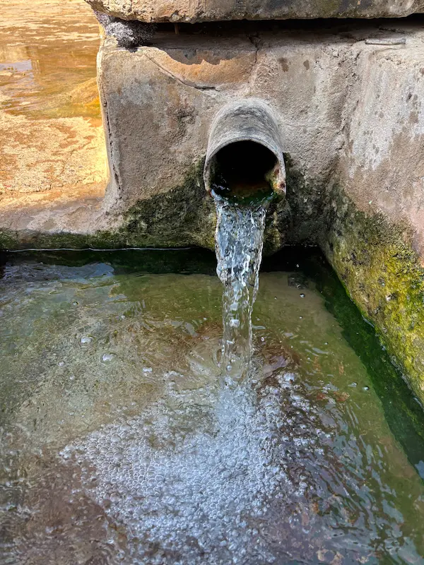Natural spring water flowing into a stone pool at the village hot spring, Midu, Dali, Yunnan.