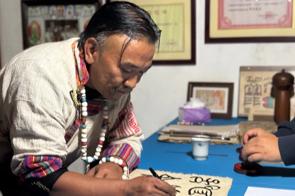 Naxi host Hekai writing Naxi Dongba pictographic script.