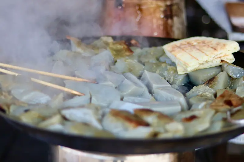 Pan-frying chicken pea jelly on a steaming hot plate at a local market in Lijiang, Yunnan.