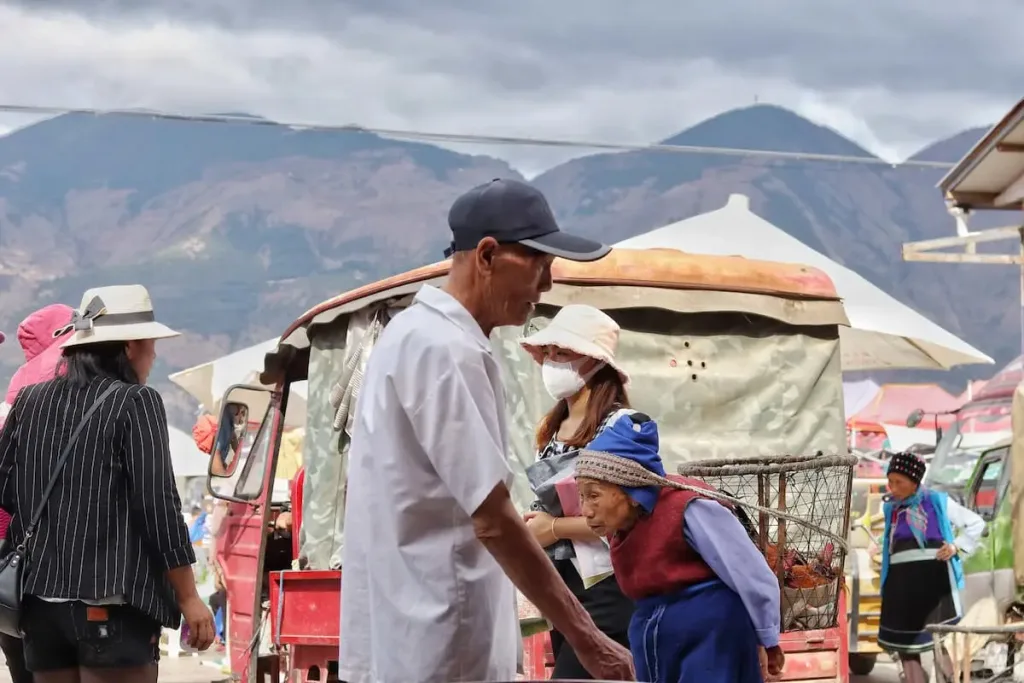 People walking through a local farmers’ market in Yunnan, with mountains in the background.