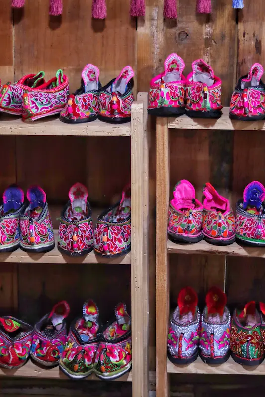 Shelves displaying colorful traditional Yi embroidered women's shoes.
