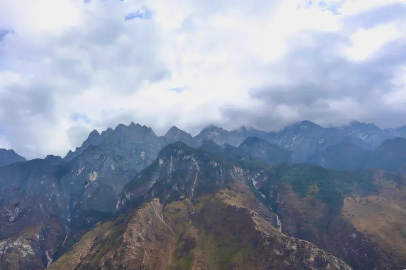 Snow-capped mountain peaks shrouded in fluffy white clouds in Yunnan.