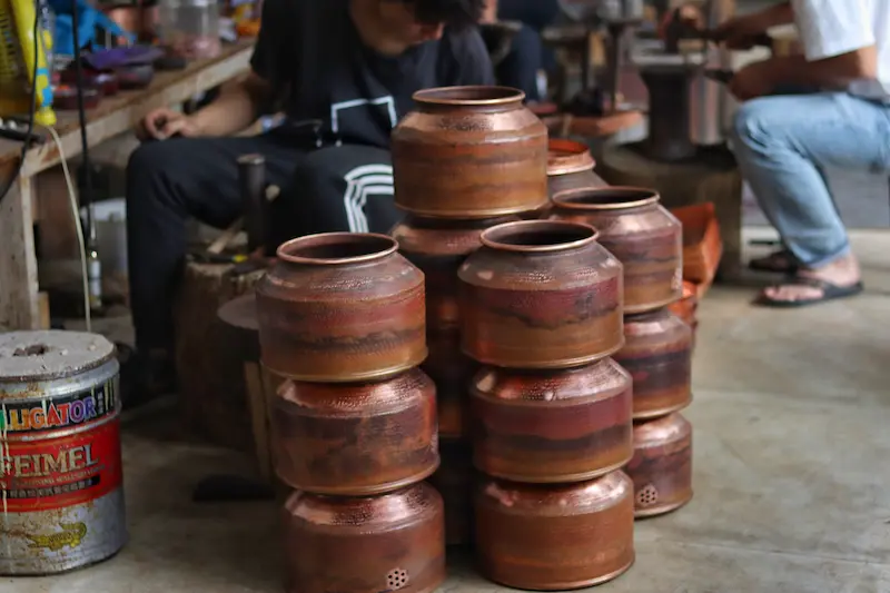 Stacked handmade copper pots at a traditional copperware workshop in Heqing, Dali, Yunnan