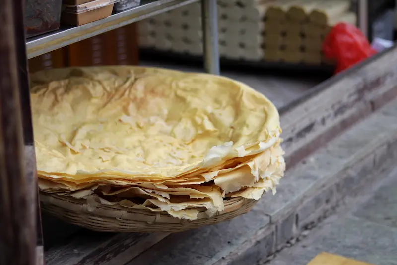 Stacked sheets of yellow pea noodle crust at a Weishan street market, Yunnan.