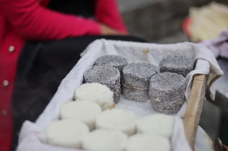 Steamed black rice and white rice cakes at a street stall in Weishan, Yunnan.