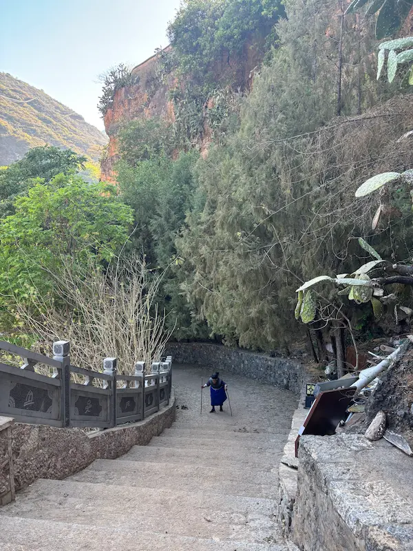 Stone steps leading down through a cliffside path in Shitou Stone Village, Lijiang, Yunnan