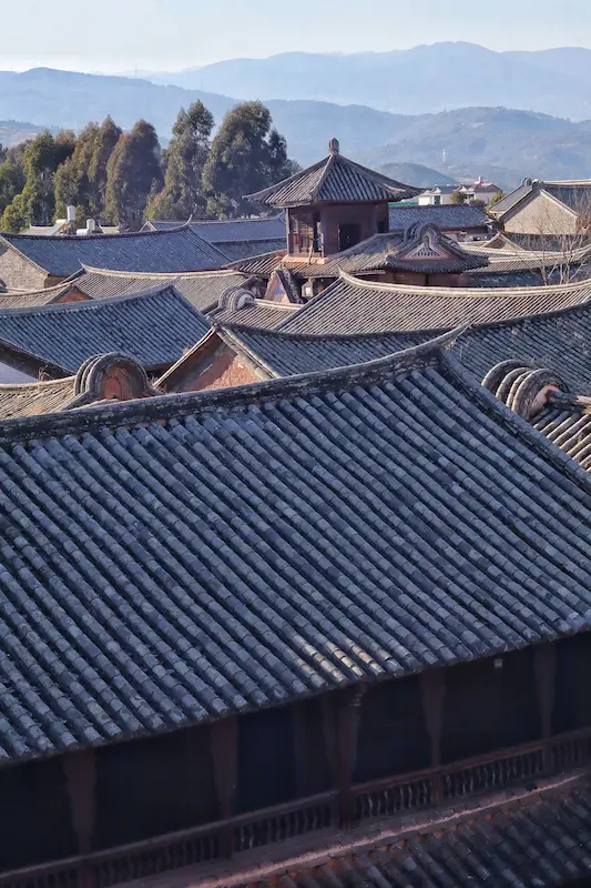 The rooftops of an ancient village with black tiles and a corner watchtower overlooking the entire village.