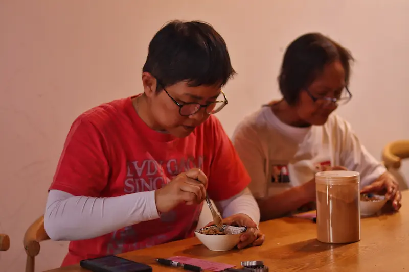 Two Singaporean guests preparing incense powder to make pendants.
