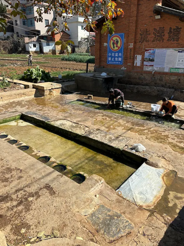 Villagers washing dishes at a stone communal hot spring pool in Midu, Dali, Yunnan.