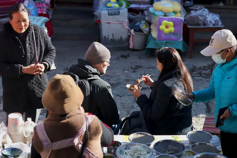 Visitors tasting pan-fried chicken pea jelly at a local market in Lijiang, Yunnan.