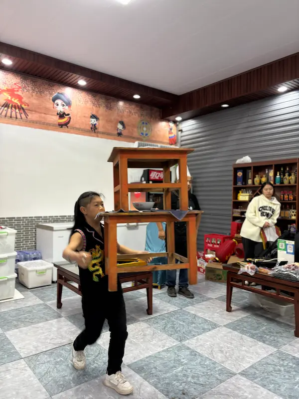 Yi minority performer balancing a stacked table on his teeth during a traditional 'jumping dishes' act in Nanjian, Dali, Yunnan.