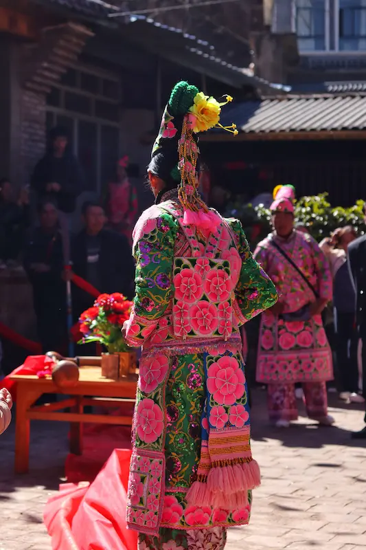 Yi villager wearing elaborate embroidered floral attire and tall headdress while attending a wedding, Nanzhao descendant village, Dali, Yunnan.