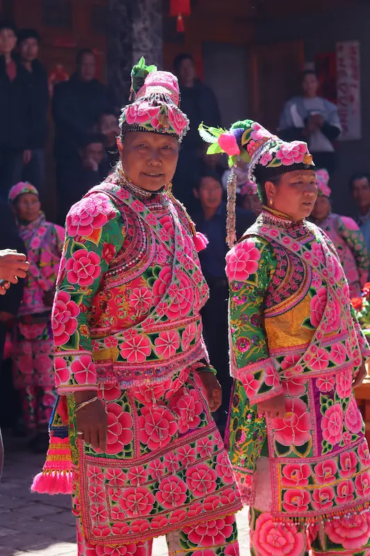 Yi women in vivid pink and green embroidered wedding attire and floral headdresses, Nanzhao descendant village, Dali, Yunnan.