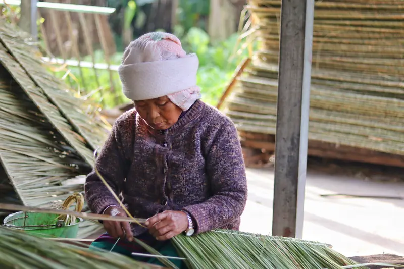 Villager weaving a traditional reed mat in a Bulang village, Yunnan