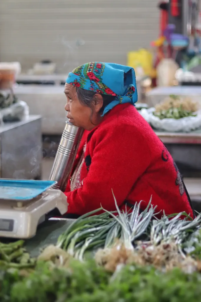 Woman selling fresh greens at a village market in Pu'er, Xishuangbanna