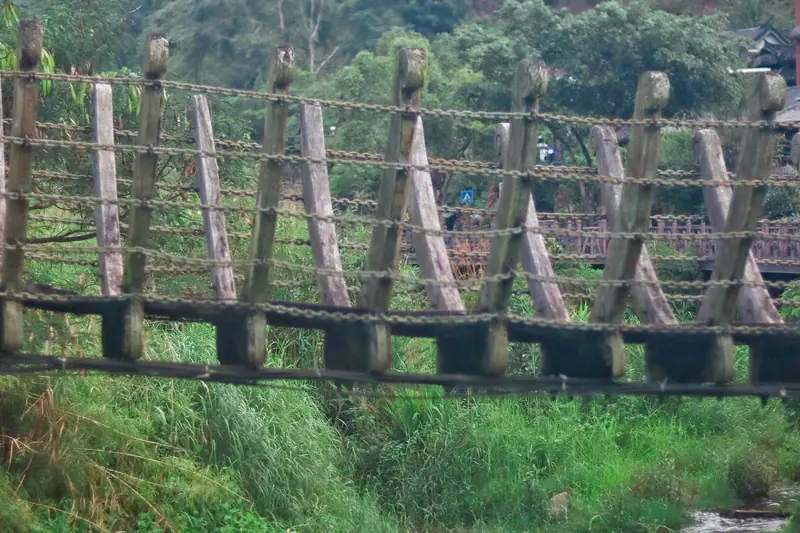 Wooden suspension bridge crossing a green valley near Pu'er