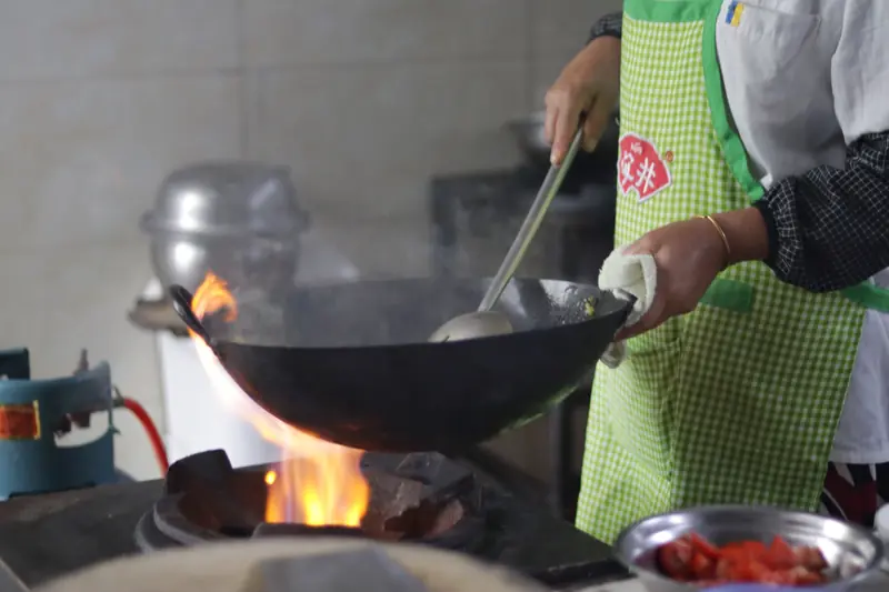 Cooking Tengchong's famous Dajiujia dish in a wok over an open fire