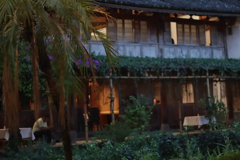 Greenery and wooden buildings at a courtyard restaurant in Tengchong