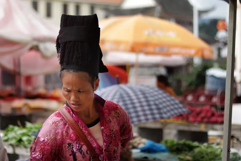 A minority woman vendor selling fresh produce at a Tengchong ethnic market