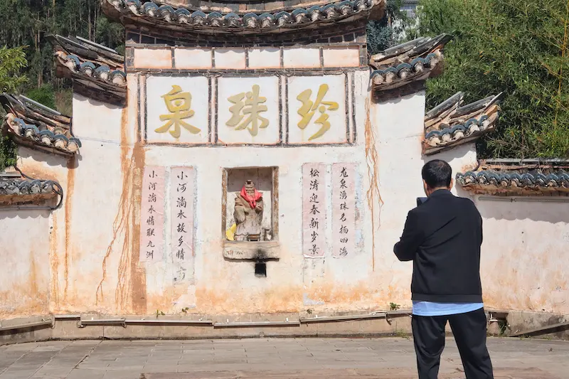 village spring water site with a white wall displaying the Chinese name of Pearl Spring.