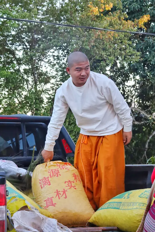 A young Bu'lang man unloading harvest sacks from a pickup truck in a Yunnan Dai village.