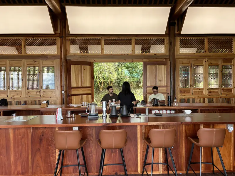 Visitors at the bar of a wooden farmhouse coffee shop at a Yunnan specialty coffee estate