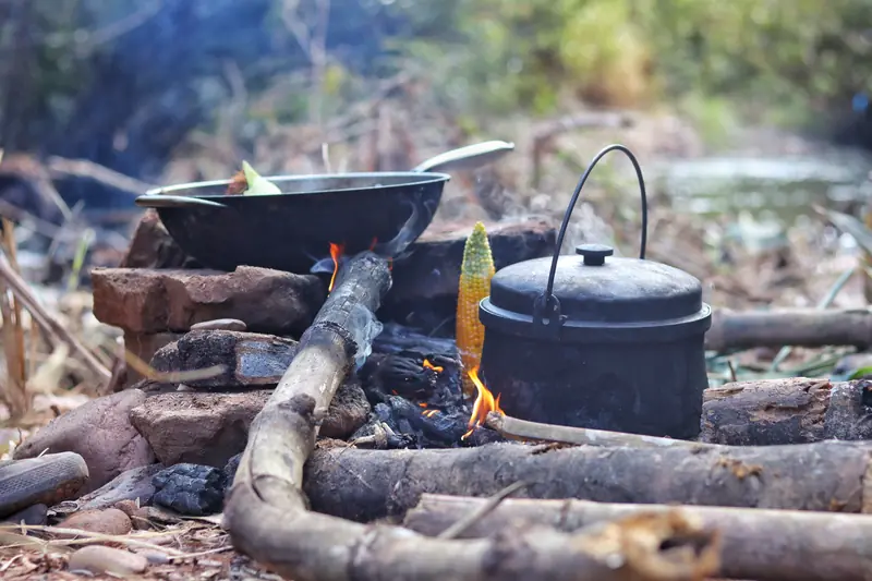 Cooking over an open fire by the river during a tea-village visit in Yunnan