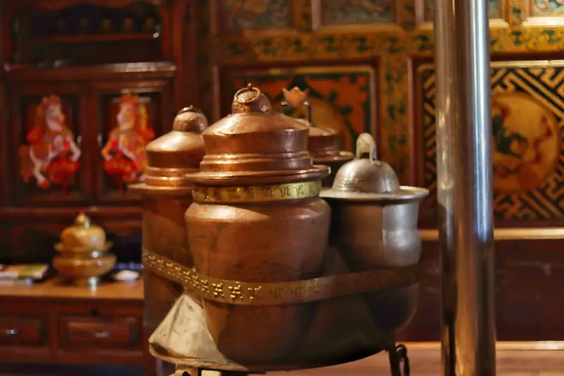 Traditional copper and brass containers used for butter tea inside a Tibetan farmhouse in Yunnan.