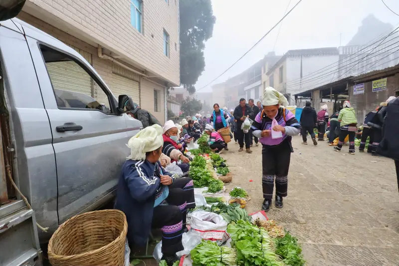 Roadside vendors with baskets of goods at a Hani market.