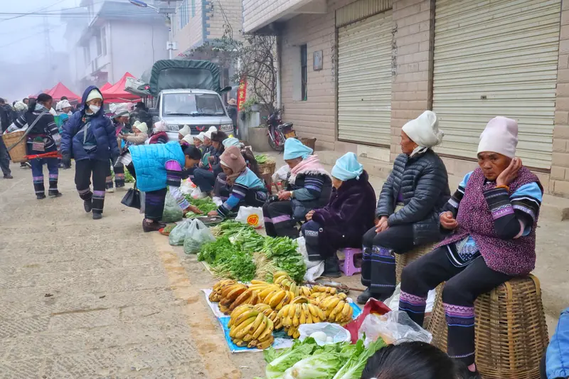 Vendors sell vegetables in the morning mist at a Hani market.