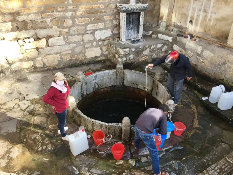 Visitors draw water from a historic well used for Jianshui's tofu-making.