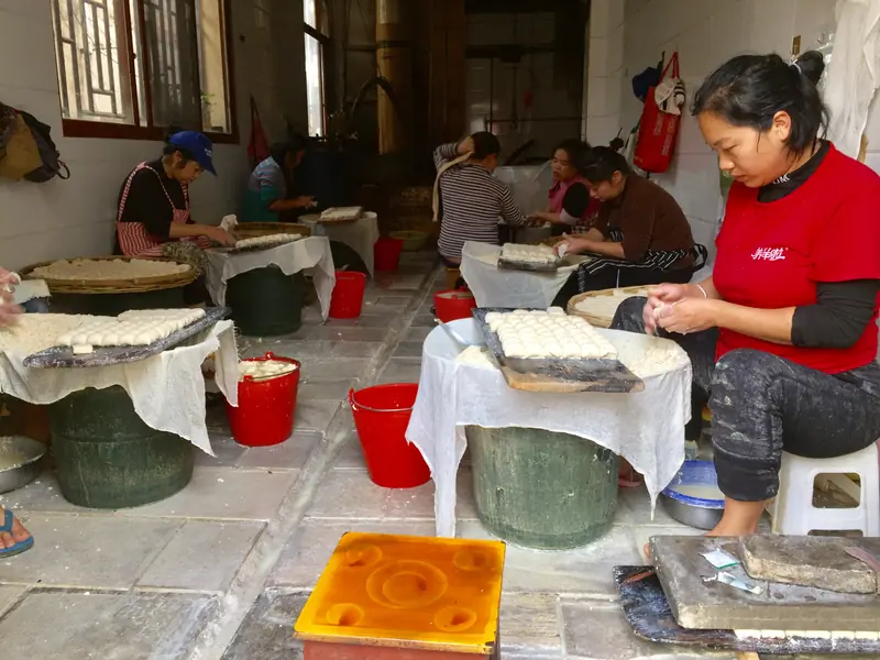 Workers press handmade tofu at a traditional Jianshui workshop.