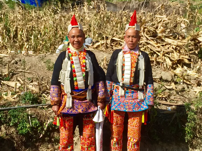 Two elders wear traditional festival dress and silver ornaments in Yunnan.